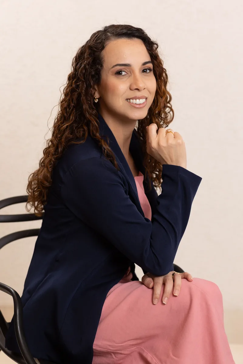Edna Costa sentada, pensativa e sorridente